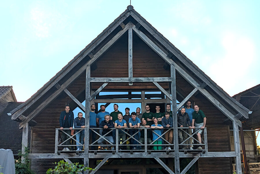 L'équipe Timberframing réunie devant une charpente en montage